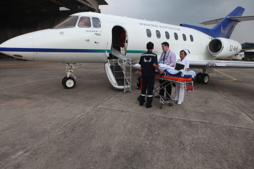 Medical team transfers a patient from an ambulance to a waiting airplane