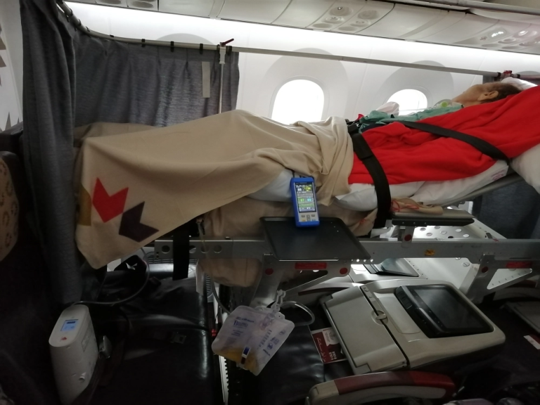 woman lying on a stretcher onboard a commercial flight.